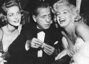 Humphrey Bogart (in tuxedo) flanked by Lauren Bacall and Marilyn Monroe.